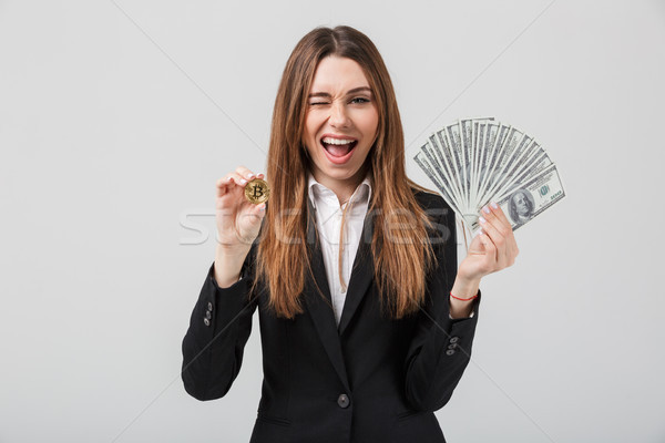 Cheerful young woman showing golden bitcoin and dollars in hands Stock photo © deandrobot