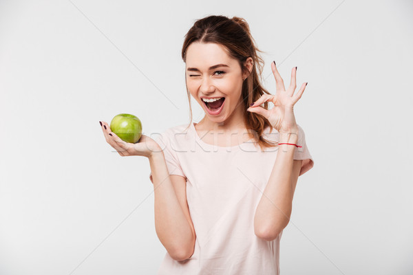 Portrait of a happy pretty girl holding an apple Stock photo © deandrobot