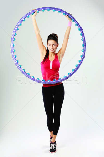 Young happy sport woman holding a massage hoop on gray background Stock photo © deandrobot