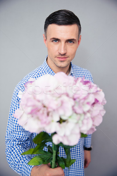 Happy man holding flowers Stock photo © deandrobot