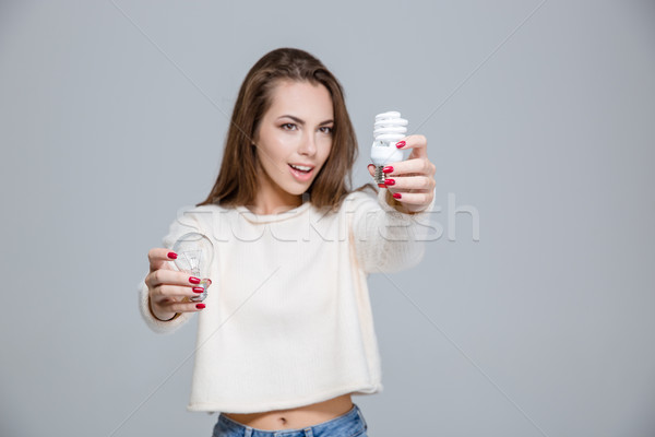 Woman holding two bulbs Stock photo © deandrobot