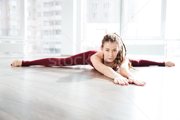 Pretty young woman lying on the floor and doing twine Stock photo © deandrobot