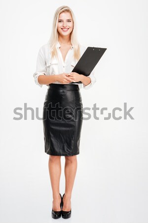 Full length of beautiful young businesswoman standing and holding clipboard Stock photo © deandrobot