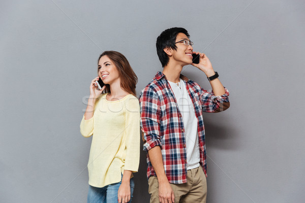 Portrait of a young multiracial couple talking on mobile phones Stock photo © deandrobot