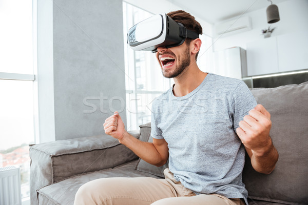 Happy man making winner gesture while wearing virtual reality device Stock photo © deandrobot