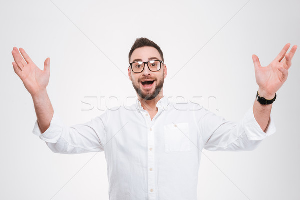 Happy young bearded man gesturing with hands Stock photo © deandrobot