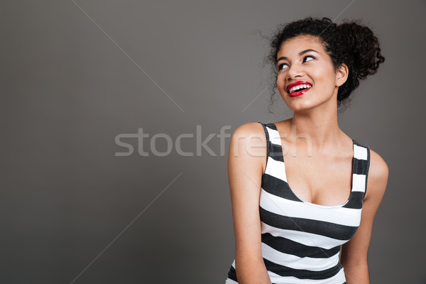 Portrait of a smiling cheerful african woman looking away Stock photo © deandrobot