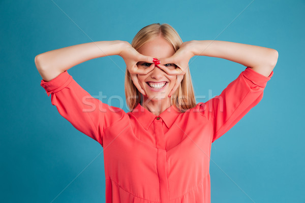 Portrait of a smiling girl looking at camera through fingers Stock photo © deandrobot