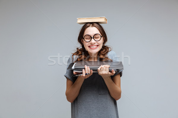 Smiling Female nerd with book on head Stock photo © deandrobot