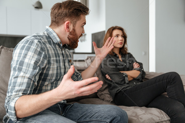 Quarrel loving couple on sofa indoors. Stock photo © deandrobot
