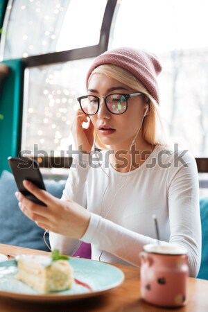 Smiling woman in hat and glasses eating cake in cafe Stock photo © deandrobot