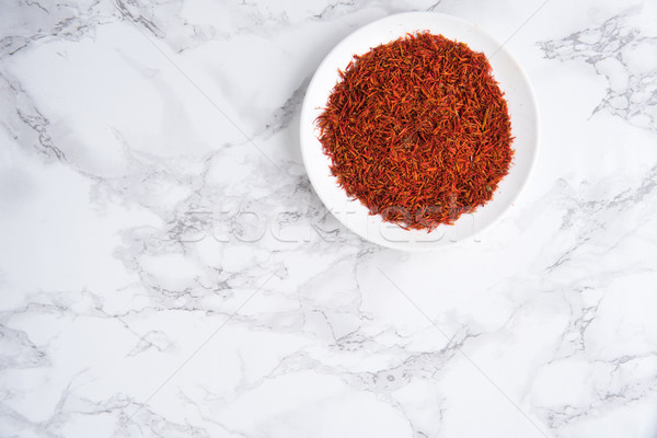 Dried saffron in small bowl isolated on white marble table Stock photo © deandrobot