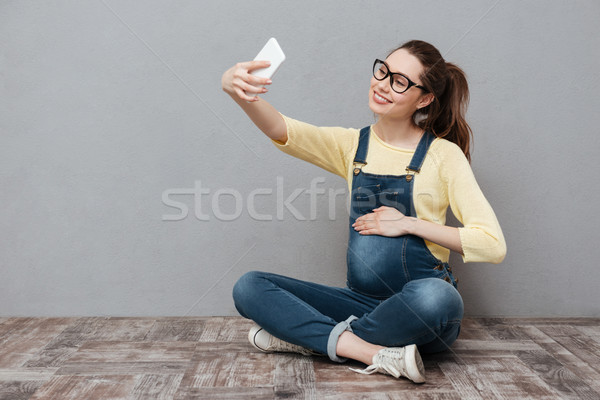 Pregnant happy woman make selfie by mobile phone. Stock photo © deandrobot