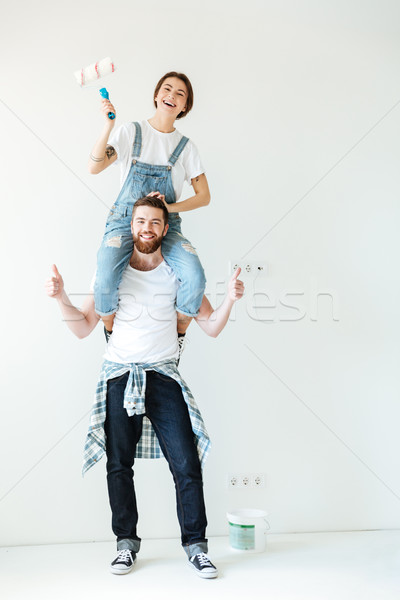 Young laughing couple holding paint rollers and looking at camera Stock photo © deandrobot