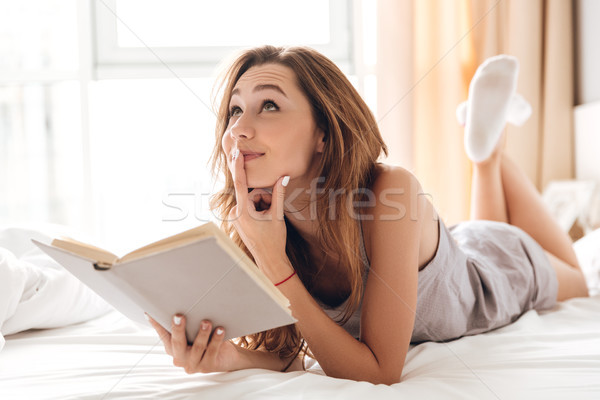 Dreaming pretty lady lies on bed indoors. Stock photo © deandrobot