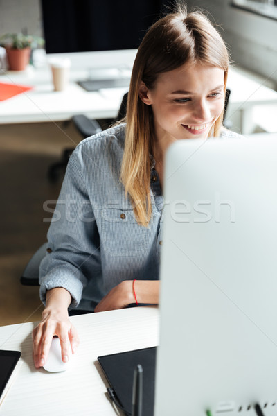 Happy young woman work in office using computer. Stock photo © deandrobot