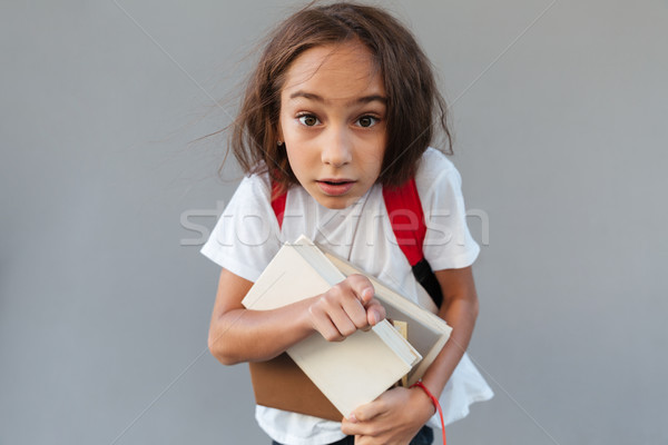 Shocked brunette schoolgirl with long hair hugging books Stock photo © deandrobot