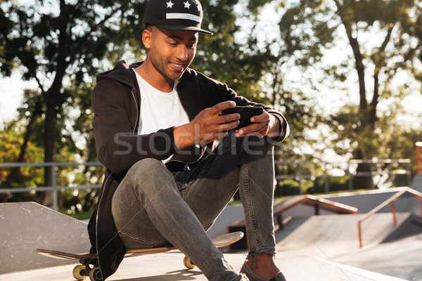 Portrait of a happy african guy using mobile phone Stock photo © deandrobot