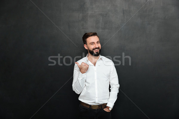 Joyous adult guy in office posing on camera, gesturing with thum Stock photo © deandrobot