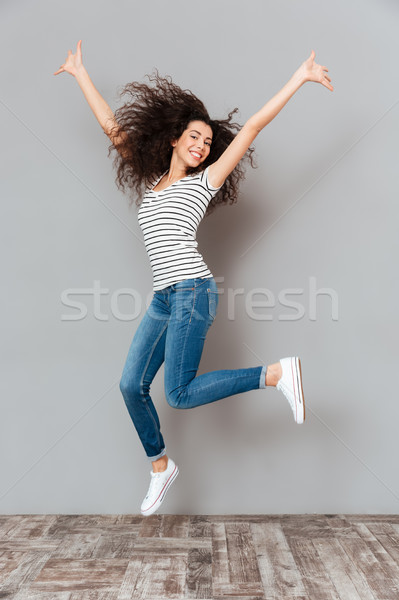 Stock photo: Joyous brunette female in casual posing on camera jumping with h