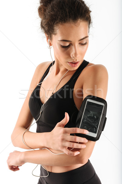 Vertical image of young curly brunette fitness woman listening music Stock photo © deandrobot