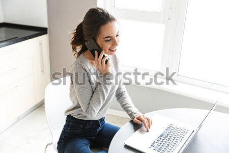 Young serious woman in striped shirt typing email to her boss wh Stock photo © deandrobot