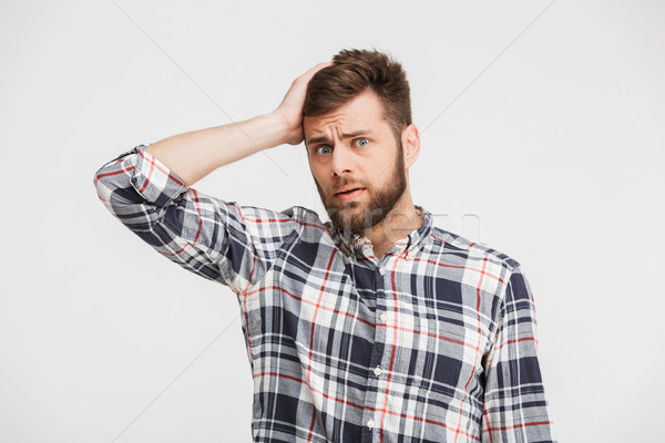 Portrait of a confused young man in plaid shirt Stock photo © deandrobot