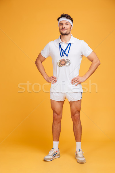 Full length of confident smiling sportsman with three medals Stock photo © deandrobot