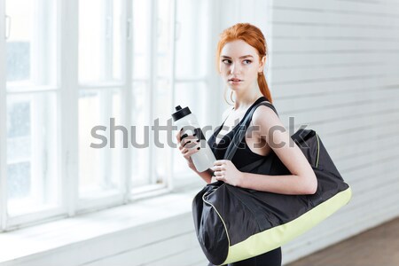 Young woman with bottle of water and sports bag Stock photo © deandrobot