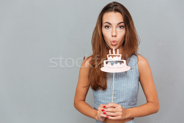Pretty cute young woman blowing on birthday cake props Stock photo © deandrobot