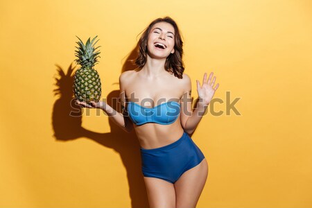 Young smiling pretty sexy girl holding pineapple and posing Stock photo © deandrobot