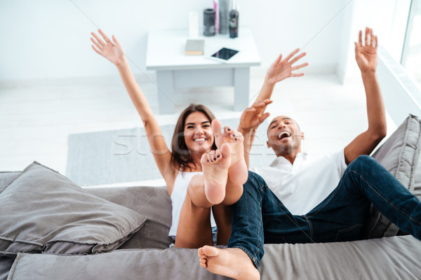 Cheerful young couple laughing and having fun on sofa Stock photo © deandrobot