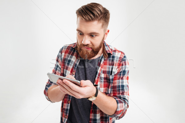 Portrait of a casual man in plaid shirt using smartphone Stock photo © deandrobot