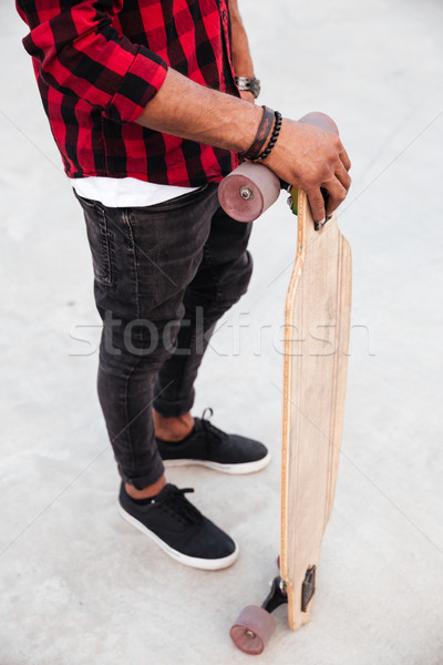 Cropped picture of young dark skinned guy holding his skateboard Stock photo © deandrobot