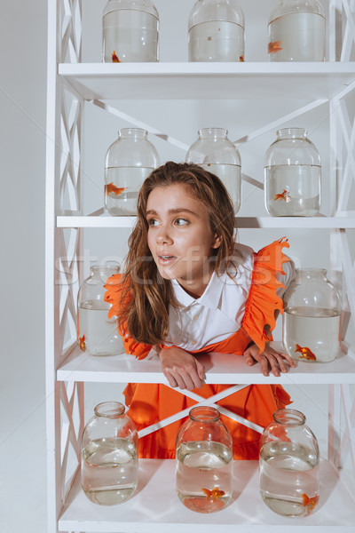 Woman standing and leaning on the shelf with gold fishes Stock photo © deandrobot