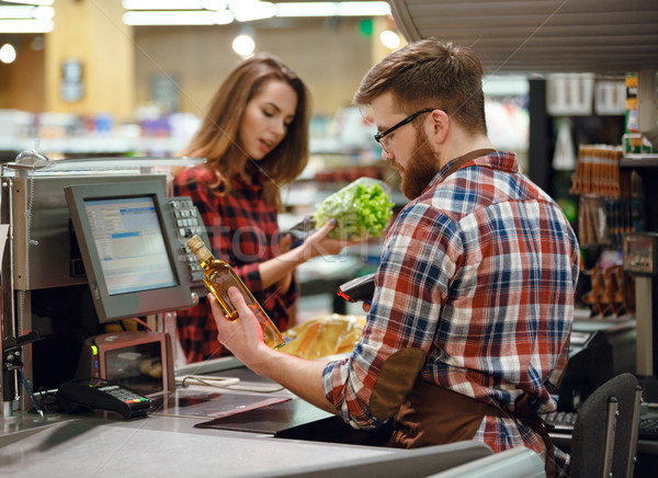 Concentrated cashier man on workspace in supermarket shop. Stock photo © deandrobot