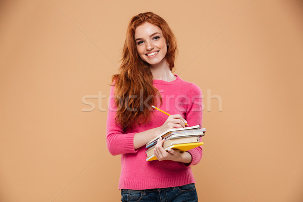 Portrait of a happy pretty redhead girl holding books Stock photo © deandrobot