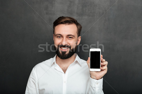 Caucasian brunette man showing smartphone on camera demonstratin Stock photo © deandrobot