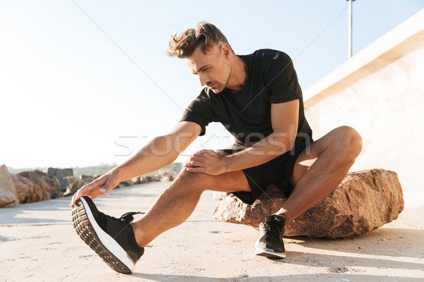 Portrait of a charming sportsman doing stretching exercises Stock photo © deandrobot