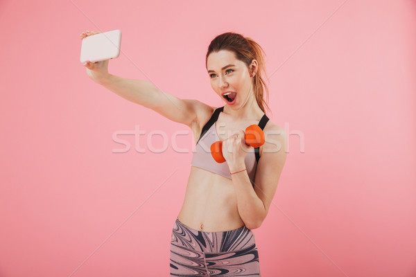 Pleased screaming sportswoman making selfie on smartphone while doing exercise Stock photo © deandrobot