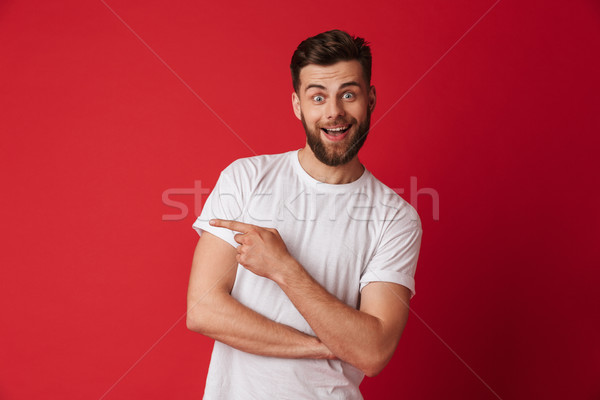 Handsome young emotional man pointing. Looking camera. Stock photo © deandrobot