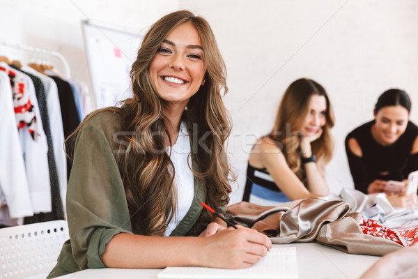 Three cheerful young women clothes designers Stock photo © deandrobot