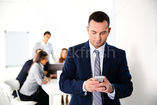 Businessman using smartphone in front of business meeting Stock photo © deandrobot
