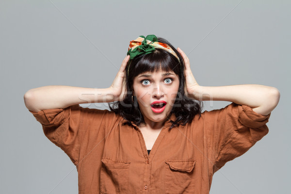 Shocked dazed woman with opened mouth holding head by hands  Stock photo © deandrobot