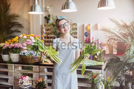 Cheerful woman florist holding two bunches of pink tulips Stock photo © deandrobot