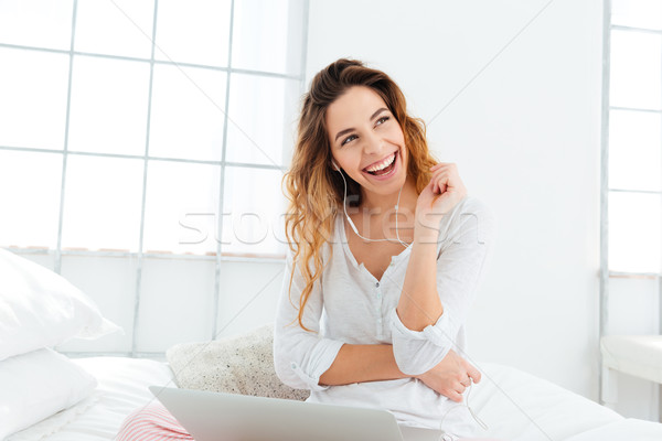 Woman with earphones and laptop computer looking away Stock photo © deandrobot