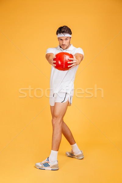 Full length of serious sports man exercising with red ball Stock photo © deandrobot