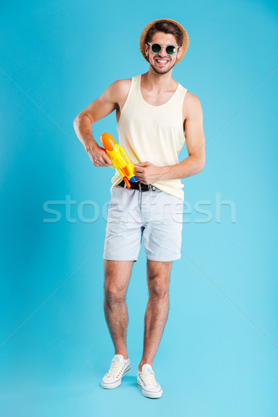 Cheerful handsome young man standing and posing with water gun Stock photo © deandrobot