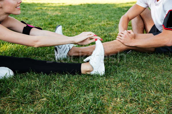 Sportive man and woman doing stretching exercises in the park Stock photo © deandrobot