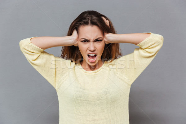 Angry stressed woman covering ears with palms and shouting Stock photo © deandrobot